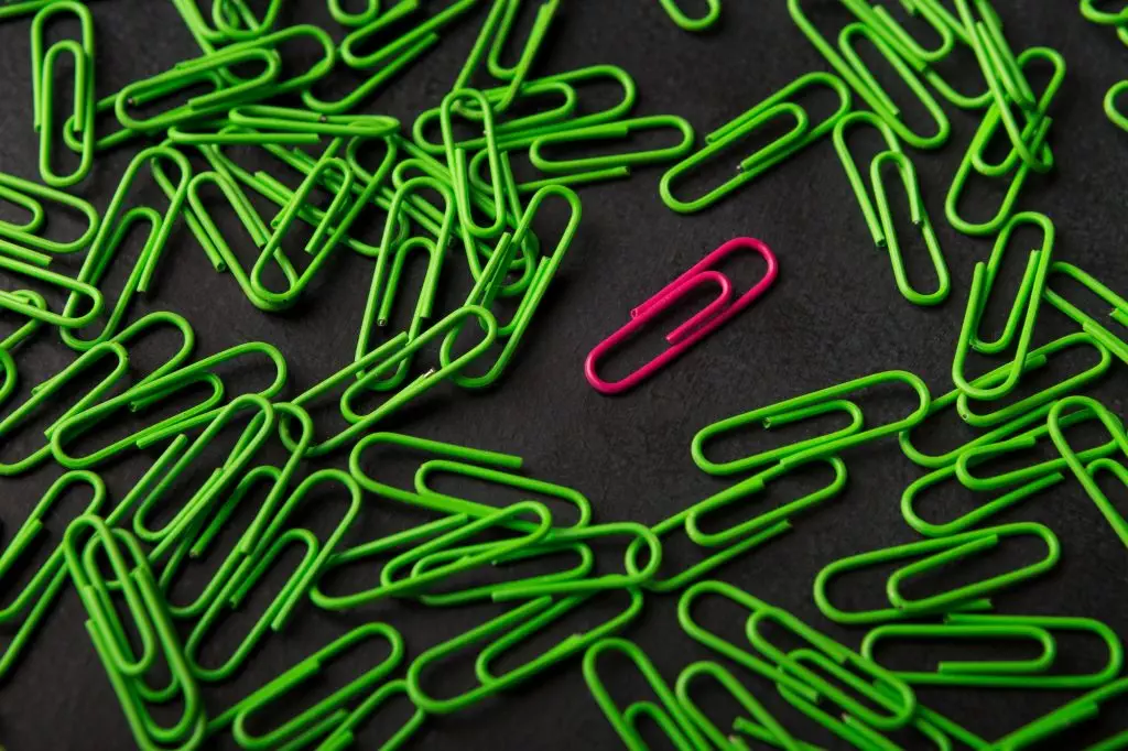 Unique pink paperclip with plenty of green ones